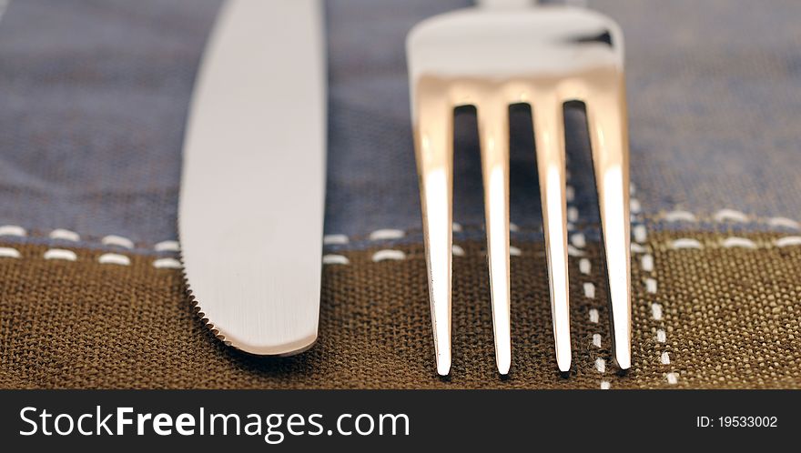 Close up fork and knife on textile napkin