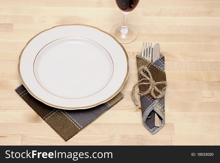 Knife and fork in textile napkin on wooden table