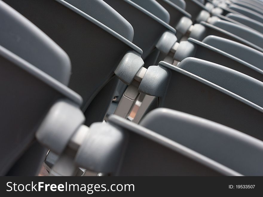 Empty grey plastic seats in rows in a stadium waiting for spectators, shallow depth of field. Empty grey plastic seats in rows in a stadium waiting for spectators, shallow depth of field