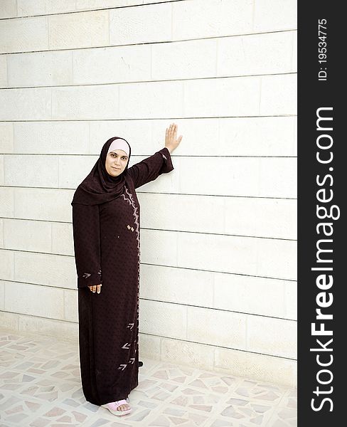 Muslim woman beside white wall