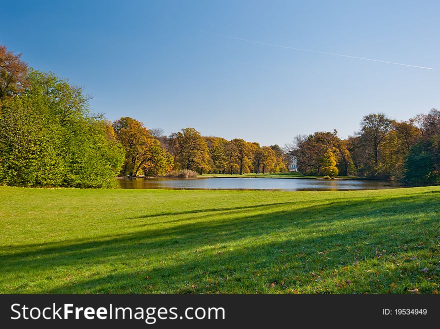 Beautiful green meadow and the pond in the autumn park. Beautiful green meadow and the pond in the autumn park