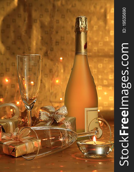 Glasses, gift boxes, candlelight and bottle of sparkling wine on gold background. Glasses, gift boxes, candlelight and bottle of sparkling wine on gold background.