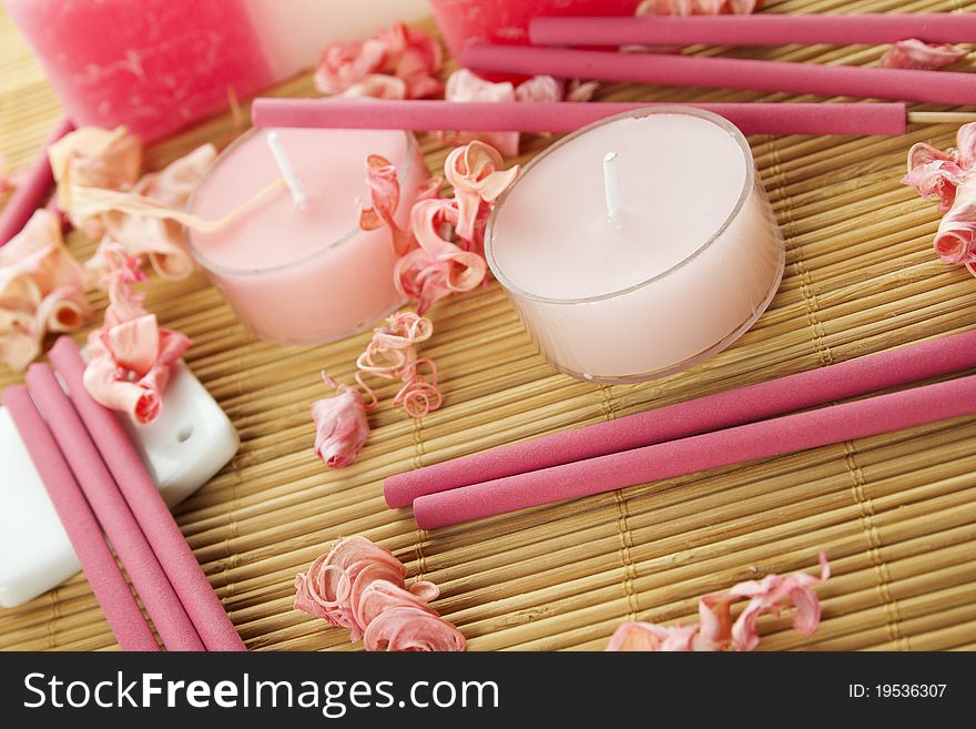 Spa treatment in bright pink and white palette, petals, candles, and arotatizirovannye sticks on a wooden bamboo rug