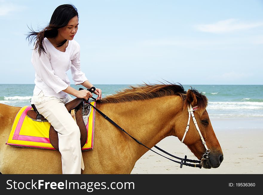 Young woman riding a horse on the beach