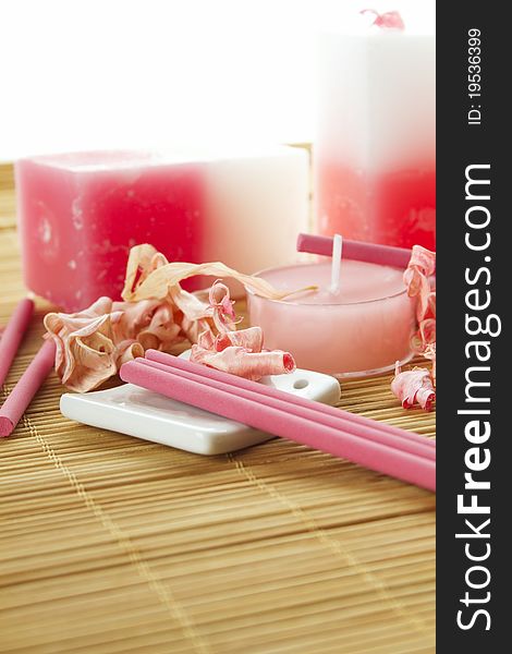 Spa treatment in bright pink and white palette, petals, candles, and arotatizirovannye sticks on a wooden bamboo rug