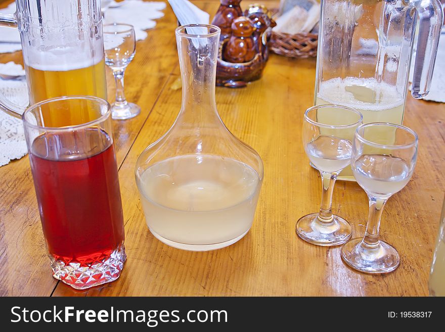 A wooden table with horseradish vodka, cherry juice, pineapple juice and beer on it. A wooden table with horseradish vodka, cherry juice, pineapple juice and beer on it