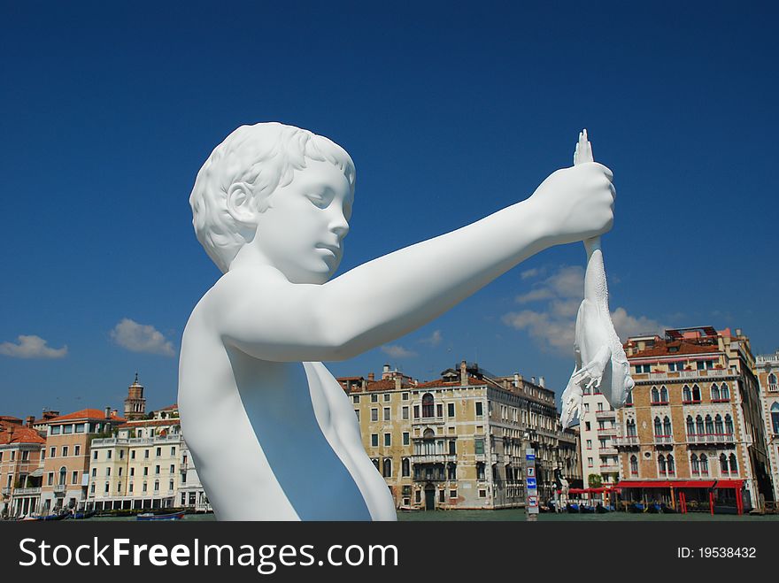 Venezia, sculpture of a boy holding a frog with the Grand Canal in the background. Venezia, sculpture of a boy holding a frog with the Grand Canal in the background