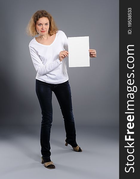 Young woman holding empty white board, on a  grey background