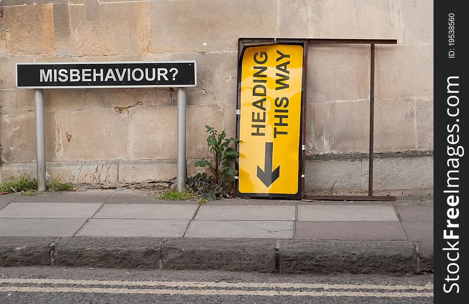 A conceptuall scene involving two British street signs situated on a pavement with block wall behind. A conceptuall scene involving two British street signs situated on a pavement with block wall behind