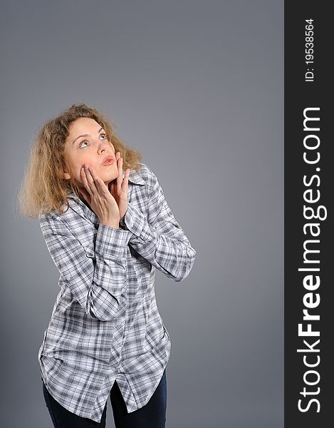 Portrait of a surprised young woman  looking upwards at copyspace against grey background