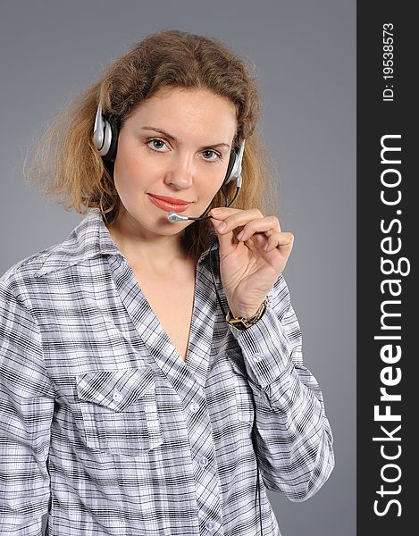 Young female customer service representative in headset, smiling on a grey background