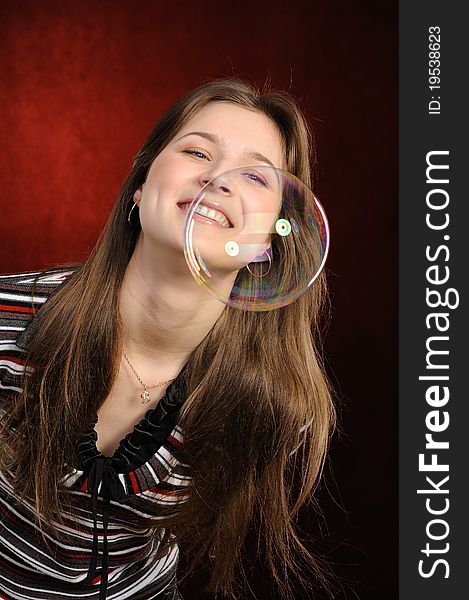 Young beautiful girl catch soap bubbles on red background. Young beautiful girl catch soap bubbles on red background