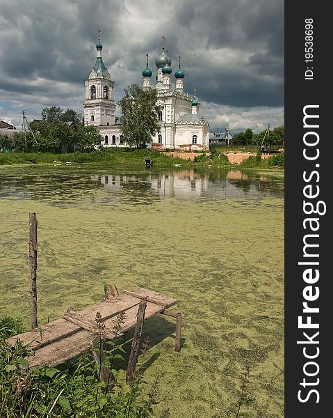 Christian temple at a pond in Dmitrovsky area of Moscow suburbs. The middle of summer. Rainy clouds are condensed over a temple. Cloudy weather. The rain will soon begin. Christian temple at a pond in Dmitrovsky area of Moscow suburbs. The middle of summer. Rainy clouds are condensed over a temple. Cloudy weather. The rain will soon begin.