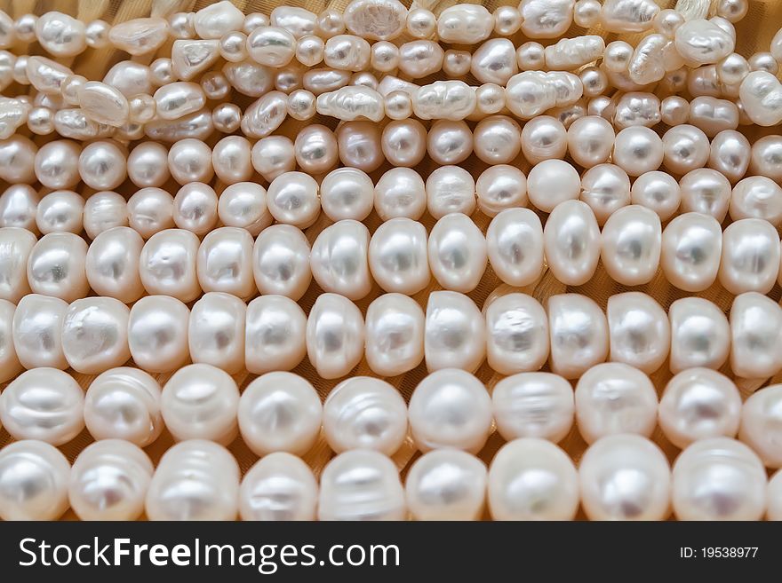 Several strands of pearls laying flat on beige background