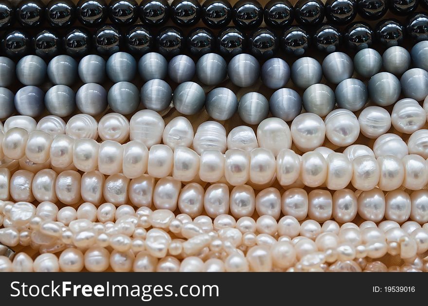 Several strands of pearls laying flat on beige background. Several strands of pearls laying flat on beige background