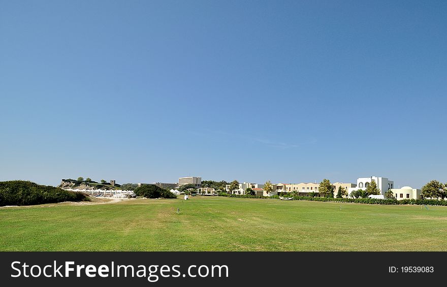 Luxury resort at the seaside, surrounded by a green field.