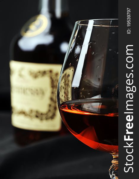 Simple composition of glass and bottle cognac. black background. Simple composition of glass and bottle cognac. black background