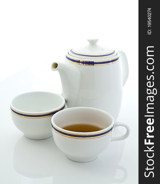 White cup of tea and teapot on white table. White cup of tea and teapot on white table
