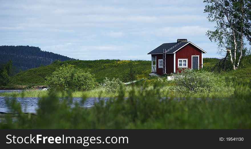 Wooden house in a green, on a riverbank in Lappland. Wooden house in a green, on a riverbank in Lappland