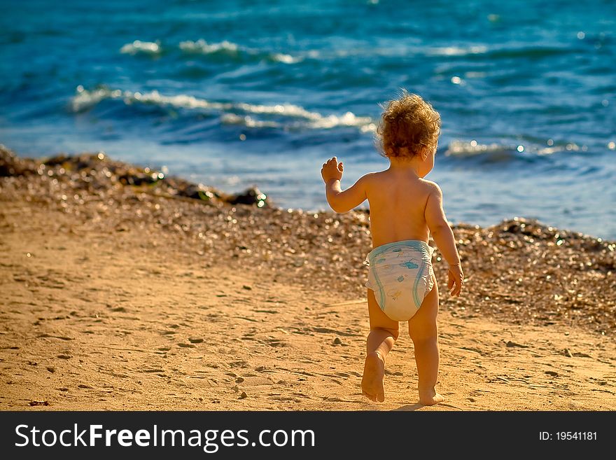 Baby boy running on the sandy beach towards the waves. Baby boy running on the sandy beach towards the waves.