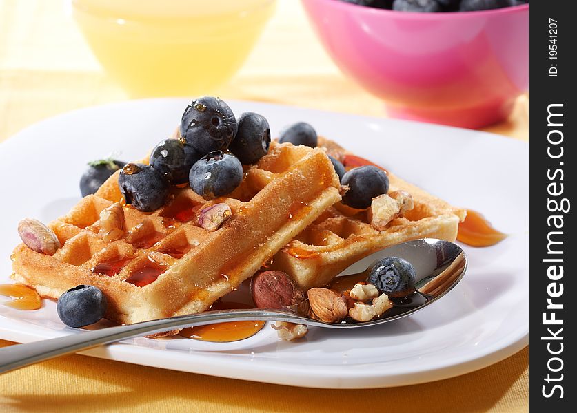 Belgian waffles with fresh blueberries and nuts on white plate