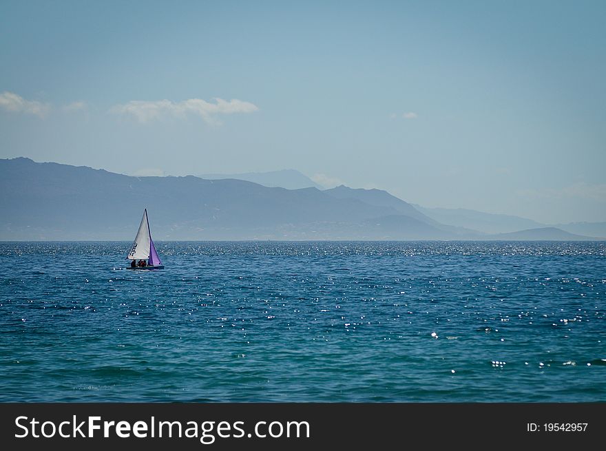 Sailing Boat in blue sea, with mountains in the background. Sailing Boat in blue sea, with mountains in the background