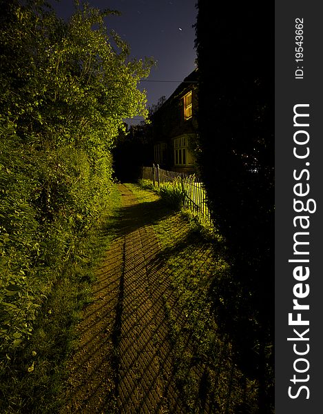 Nighttime scene of a footpath lit by window light. Nighttime scene of a footpath lit by window light