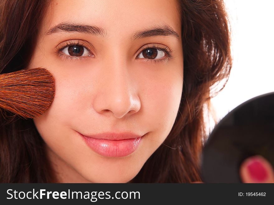 Beautiful young woman making up her face with a small smile on her lips