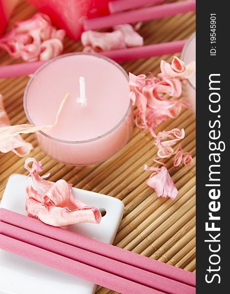 Spa treatment in bright pink and white palette, petals, candles, and arotatizirovannye sticks on a wooden bamboo rug