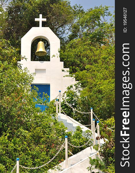 A small white church building with bell among green plant on hill, beside sea coast of Shenzhen, China. A small white church building with bell among green plant on hill, beside sea coast of Shenzhen, China.