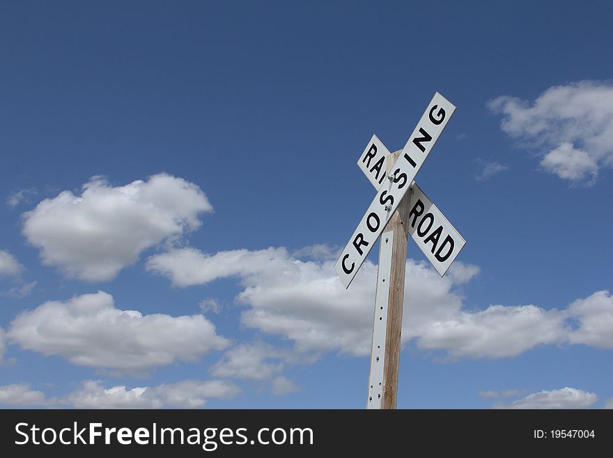 Railroad crossing sign against blue sky