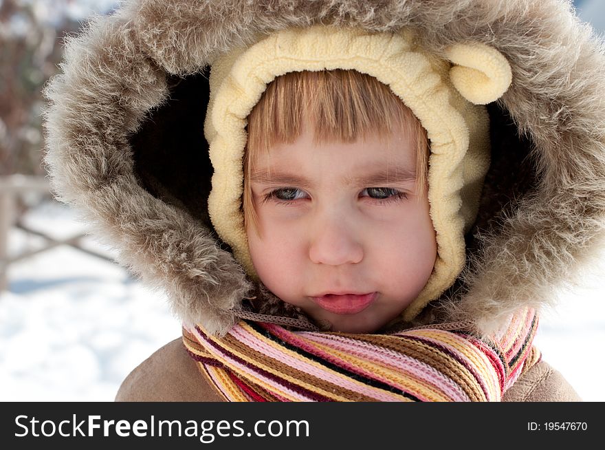 Winter outdoors head and shoulders portrait of a little girl wearing fir-coat with hood and scarf. Winter outdoors head and shoulders portrait of a little girl wearing fir-coat with hood and scarf