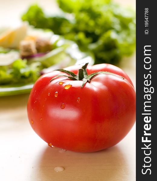 Fresh ripe tomato with salad on background. Shallow depth of field, selective focus