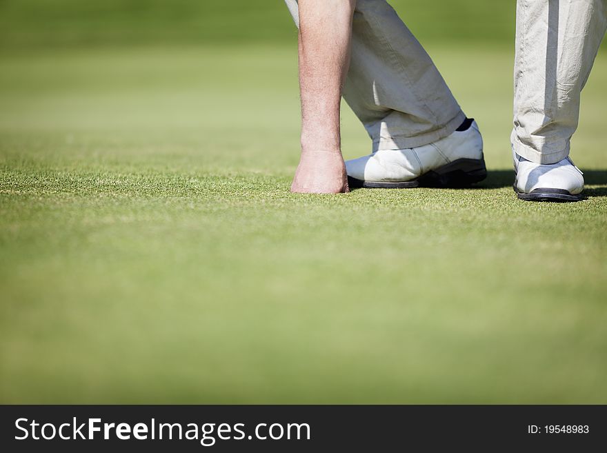 Close up of male golf player picking up ball from hole at green, with plenty of copy space. Close up of male golf player picking up ball from hole at green, with plenty of copy space.