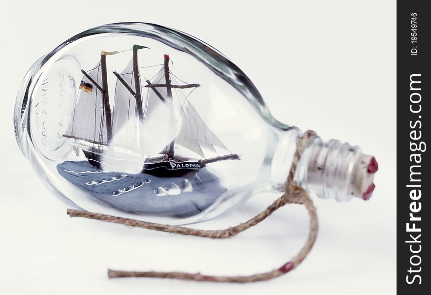 The image shows a ship in a bottle over white