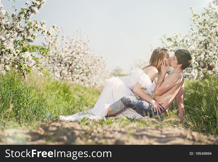 Beautiful young couple kissing in the flowering gardens