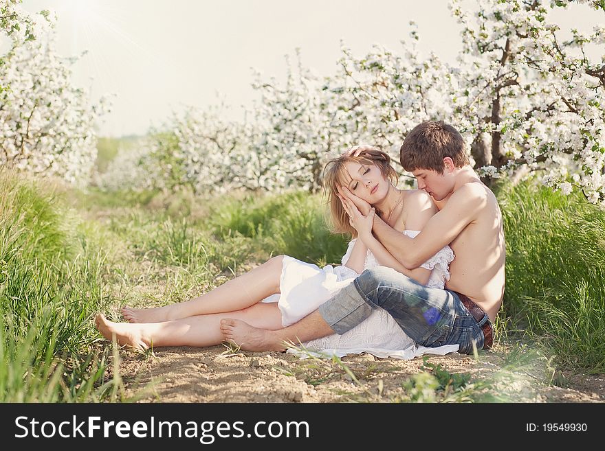 Beautiful young couple kissing in the flowering gardens