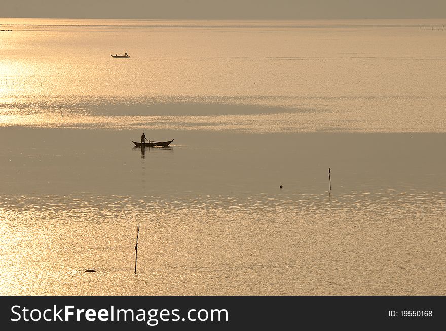 Fisherman on a wooden boat in an early golden morning hour. Fisherman on a wooden boat in an early golden morning hour