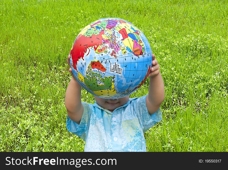 Boy holding the earth model on the grass