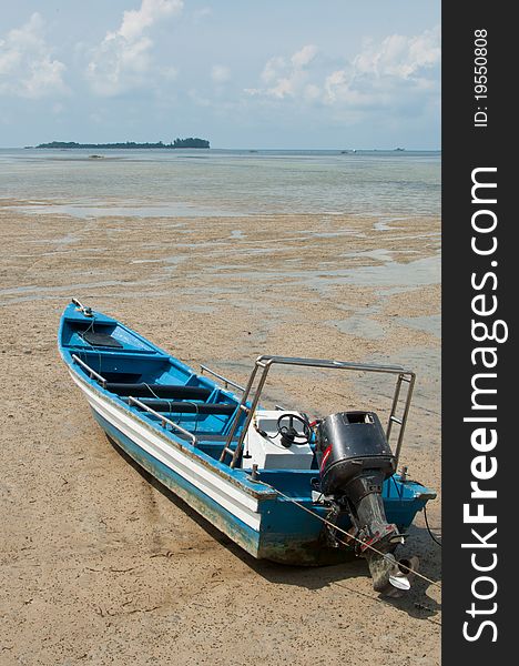 An immobilized wooden boat stranded on a beach during low tide