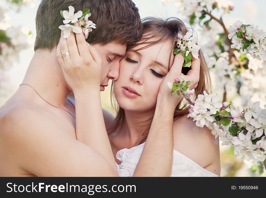 Beautiful young couple kissing in the flowering ga