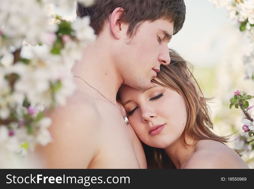 Beautiful young family kissing in the flowering gardens. Beautiful young family kissing in the flowering gardens