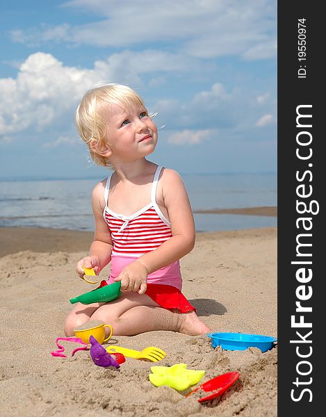 Child plays with toy in sand on beach