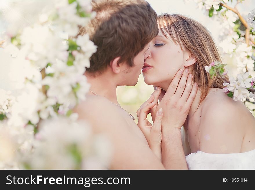 Beautiful young family kissing in the flowering gardens. Beautiful young family kissing in the flowering gardens