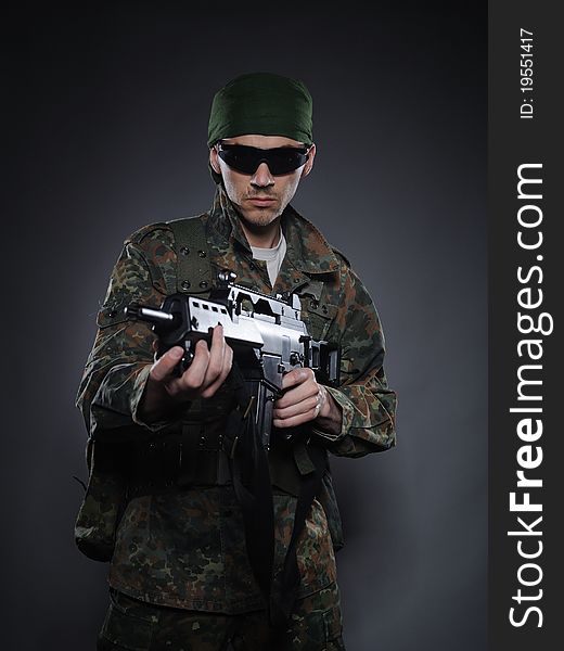 Young soldier in camouflage and ammunition with a gun. studio shot. Young soldier in camouflage and ammunition with a gun. studio shot