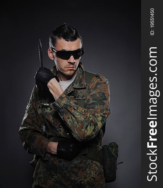 Portrait of soldier in camouflage and ammunition with knife. studio shot