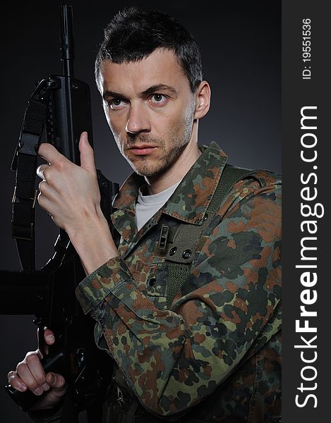 Young soldier in camouflage and ammunition with a gun. studio shot. Young soldier in camouflage and ammunition with a gun. studio shot