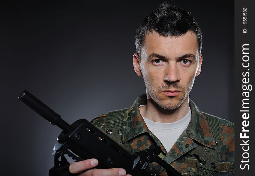 Young soldier in camouflage and ammunition with a gun. studio shot. Young soldier in camouflage and ammunition with a gun. studio shot