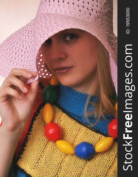 Funny Girl in a big hat and a multicolored knitted cape
