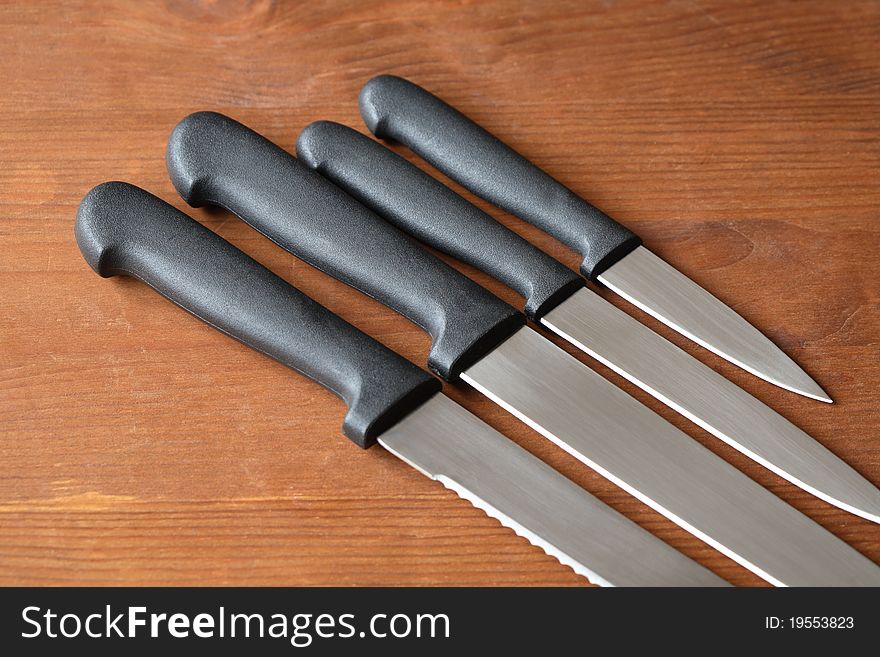 Kitchen knives set in a row on wooden surface